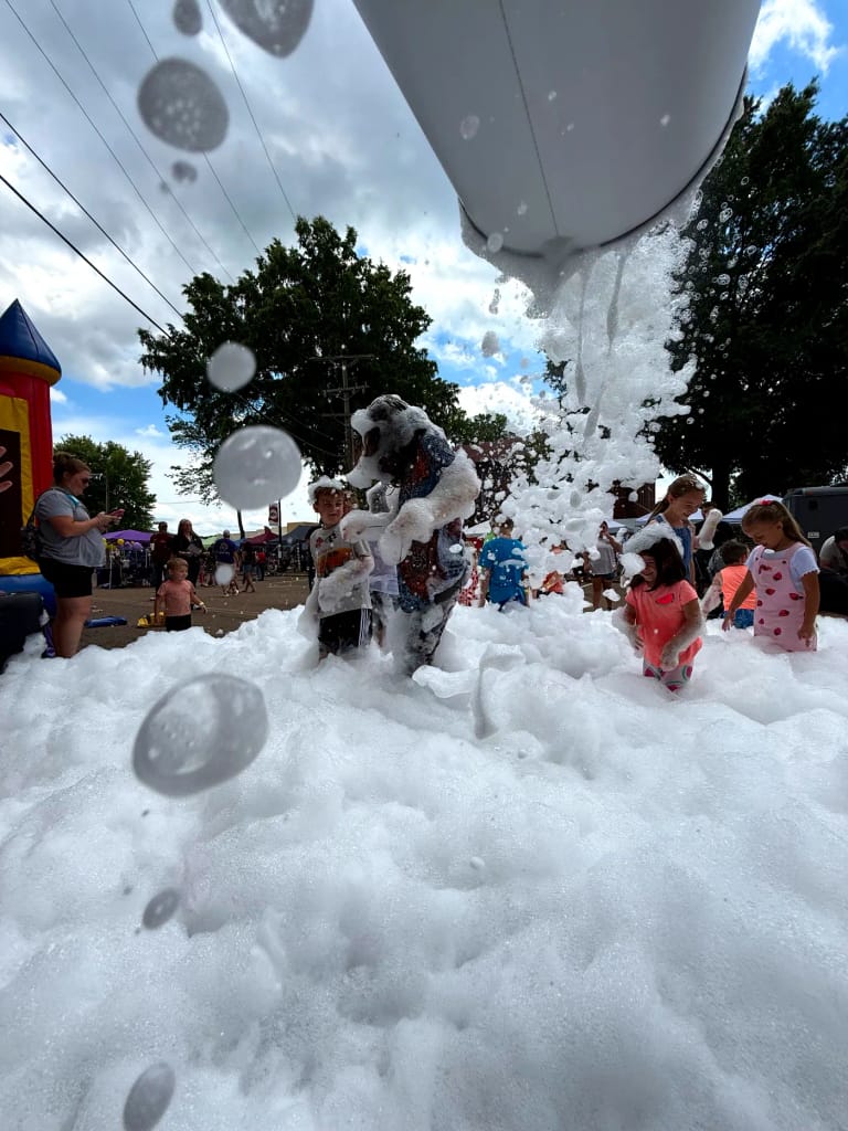 A toddler reaching for foam at an Elite Foam Experiences event