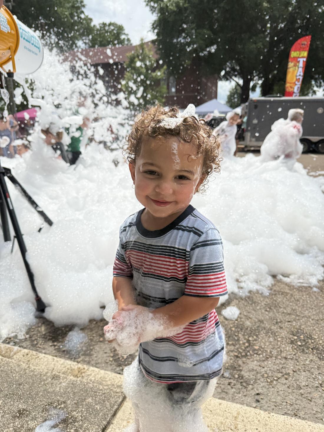Smiling child covered in foam at an Elite Foam Experiences event